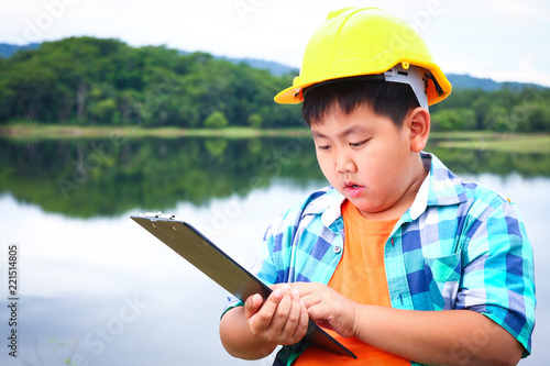 The boy wants to be a dam engineer. Put on a yellow safety hat. Stand by the documents in your hand.