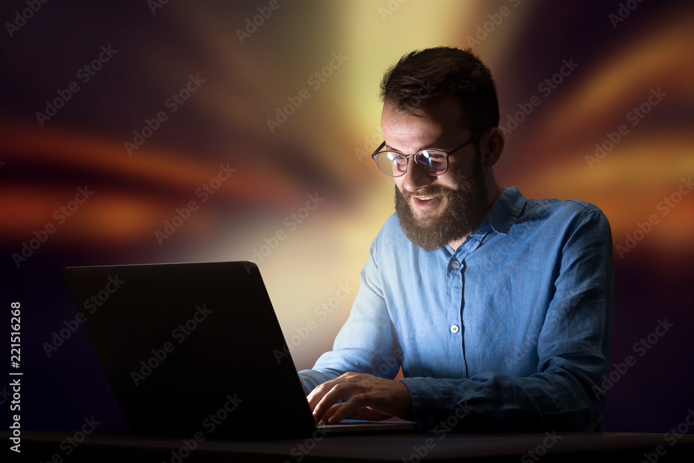 Young handsome businessman working late at night in the office with warm lights in the background Young handsome businessman working late at night in the office with warm lights in the background