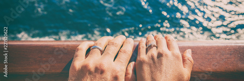 Wedding bands newlyweds couple on honeymoon travel on cruise ship boat. Closeup of hands against ocean sea background. Panoramic banner.