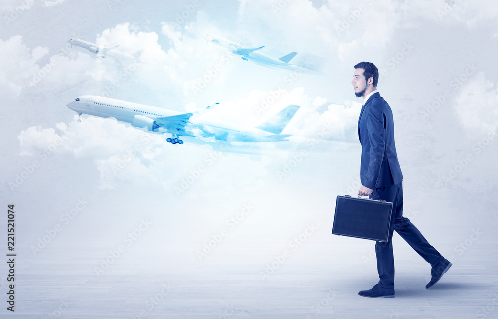 Obraz premium Elegant businessman going somewhere with briefcase and airplane on the background 
