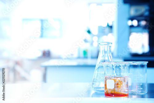 flask beaker with orange solution in science research education laboratory background