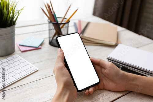 hand woman using a telephone, empty screen smart phone and computer on wooden table In home office. with clipping path