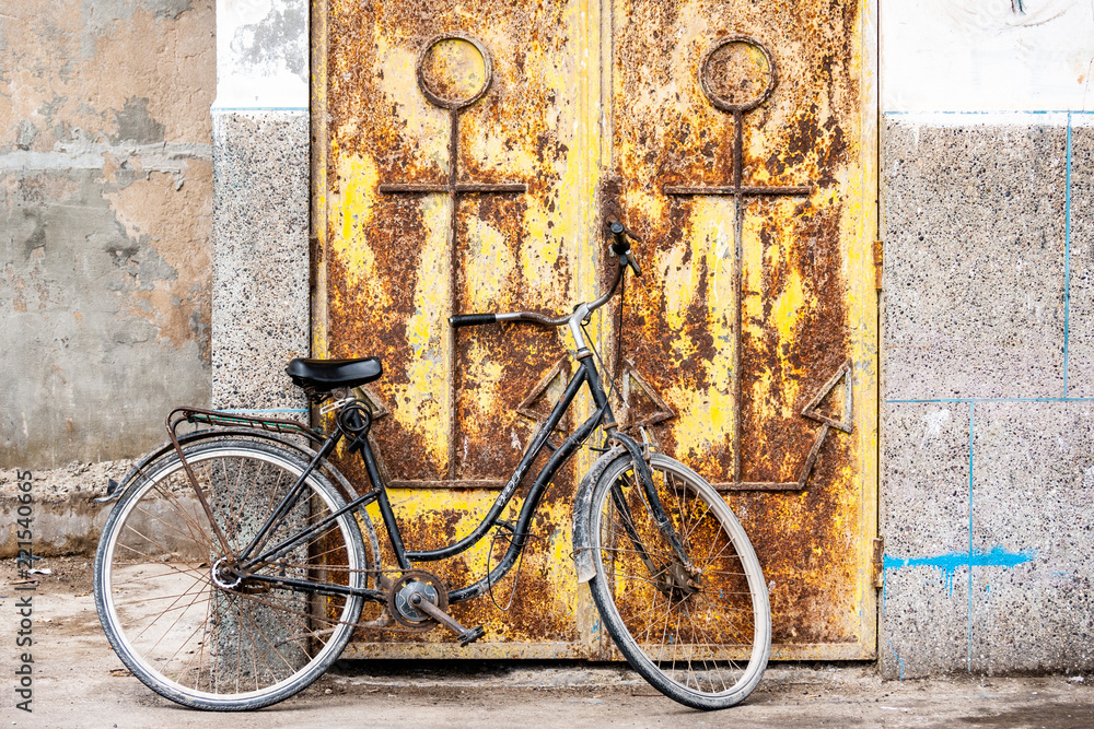 A bicycle is leaning against the condemned door of an abandoned house in the Mellah district of Essaouira, Morocco