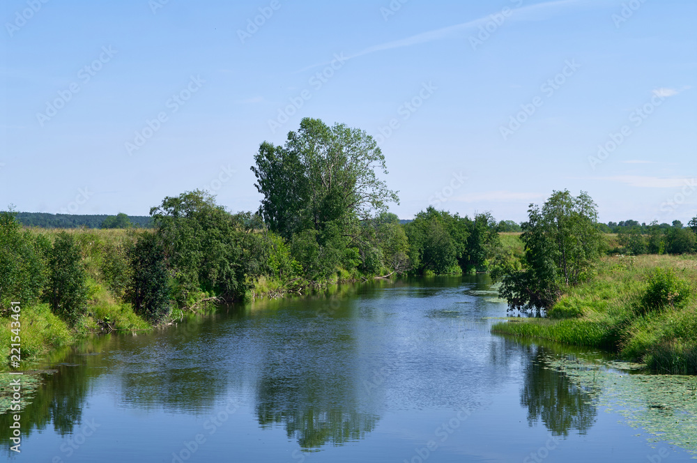 Summer landscape on a sunny day. The river flows among small trees and meadows Summer landscape on a sunny day. The river flows among small trees and meadows