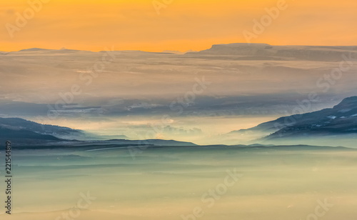 Mountains in the fog  haze. The Main Caucasian Range. Multicolored background. Mountains at sunset. Winter fog.