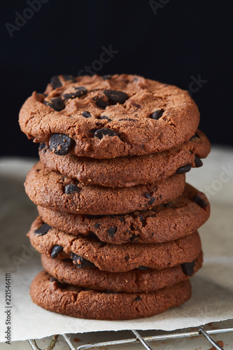 A pile of chocolate cookies with chocolate chips on baking paper