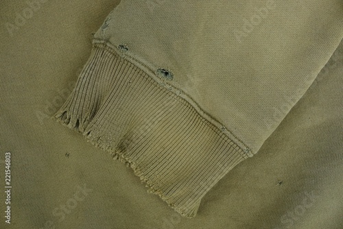 green fabric texture with a sleeve of a piece of ragged old clothes