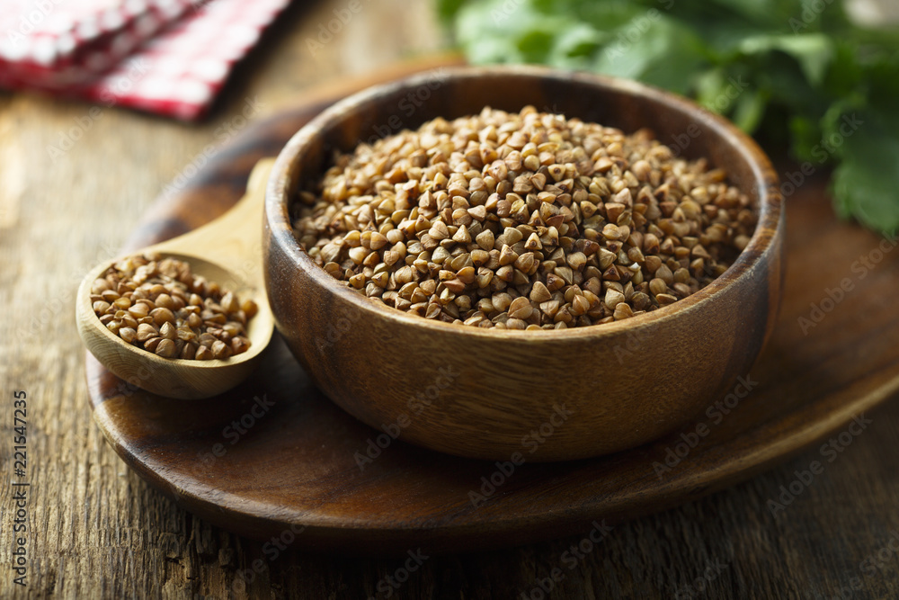 Raw buckwheat in the wooden bowl Raw buckwheat in the wooden bowl