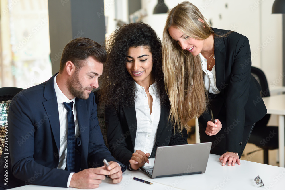 Multi-ethnic group of three businesspeople meeting in a modern office. Multi-ethnic group of three businesspeople meeting in a modern office.