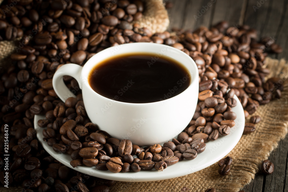 Coffee cup and beans on a rustic background. Coffee Espresso and a piece of cake with a curl. Cup of Coffee and coffee beans on table. Coffee cup and beans on a rustic background. Coffee Espresso and a piece of cake with a curl. Cup of Coffee and coffee beans on table.