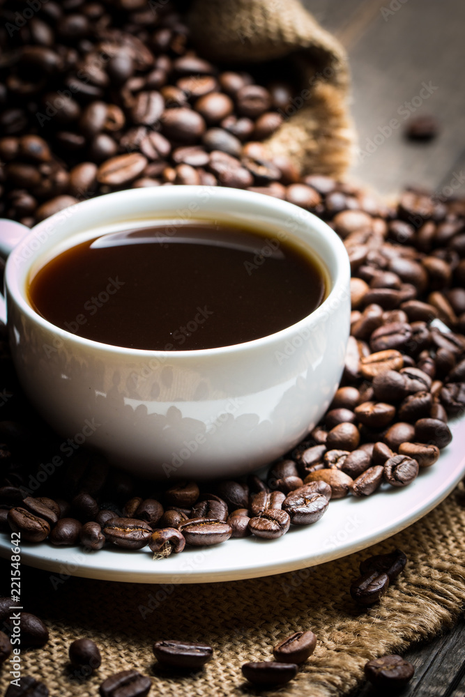Coffee cup and beans on a rustic background. Coffee Espresso and a piece of cake with a curl. Cup of Coffee and coffee beans on table. Coffee cup and beans on a rustic background. Coffee Espresso and a piece of cake with a curl. Cup of Coffee and coffee beans on table.