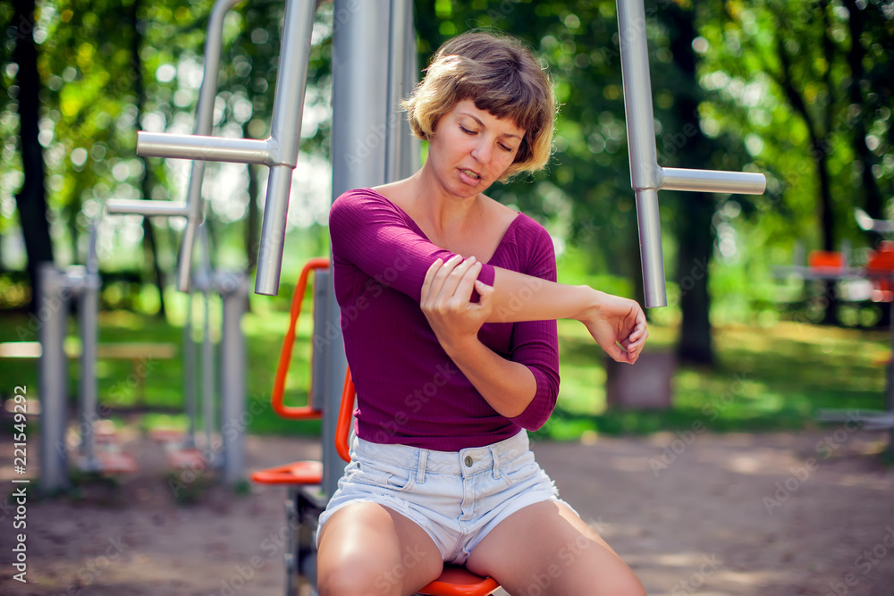 Young woman feeling pain in her elbow, hand during sport workout in the park. Sport, medicine and people concept Young woman feeling pain in her elbow, hand during sport workout in the park. Sport, medicine and people concept