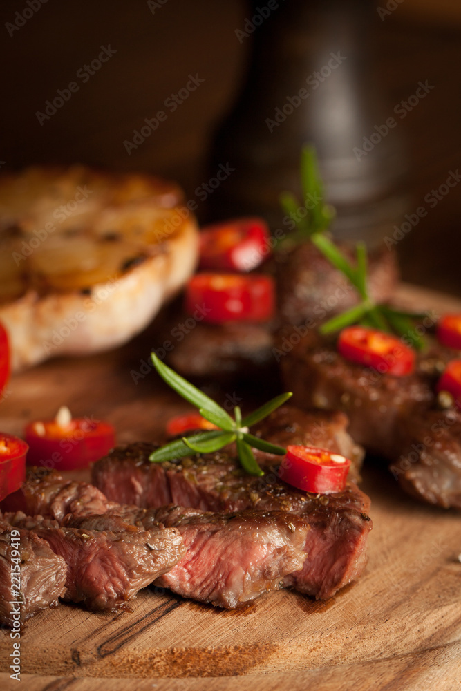 grilled fillet steak with tomatoes and roast vegetables on an old wooden board, background.