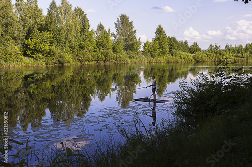 A boy is fishing on a raft on a river