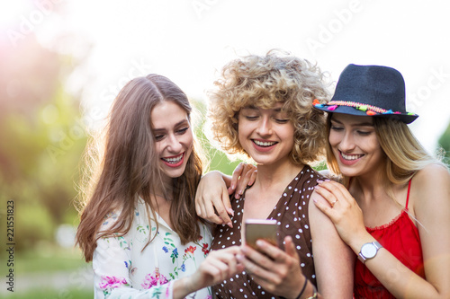 Three happy young women having fun with smart phone  