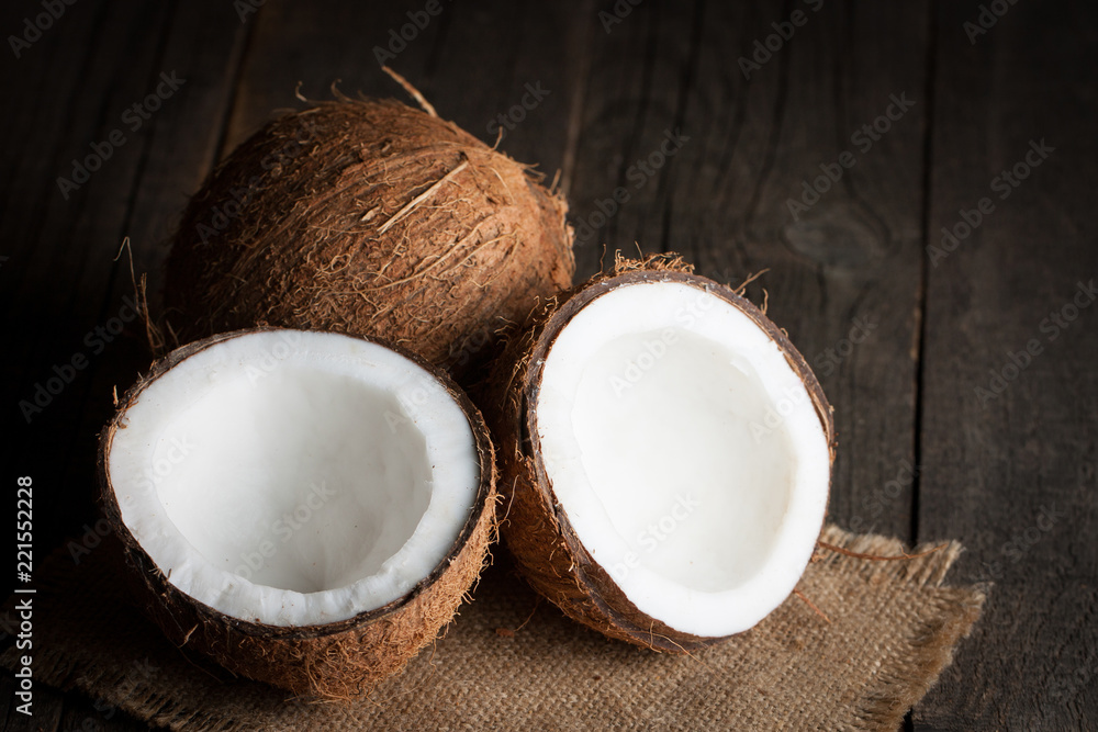 Ripe half cut coconut on a wooden background. Ripe half cut coconut on a wooden background. Coconut cream and oil. Ripe half cut coconut on a wooden background. Ripe half cut coconut on a wooden background. Coconut cream and oil.