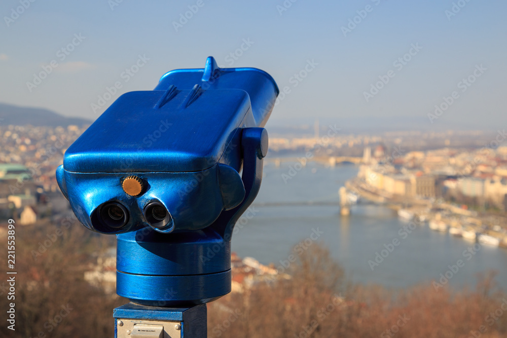 Blue binoculars and defocused panorama view of the famous Hungarian Parliament across the river Danube, Budapest