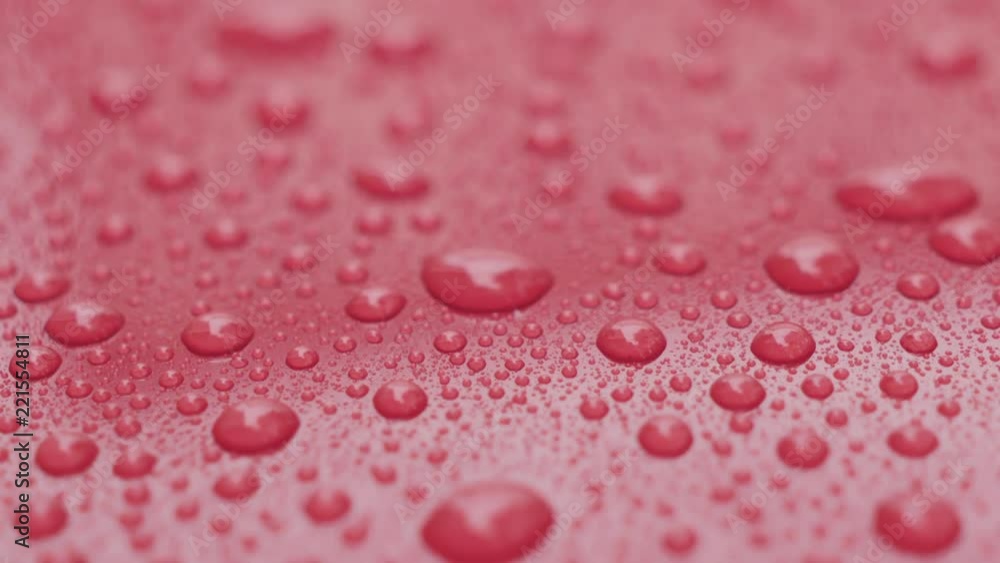 Slow motion handheld pan of water drops on red car with hydrophobic coating Slow motion handheld pan of water drops on red car with hydrophobic coating