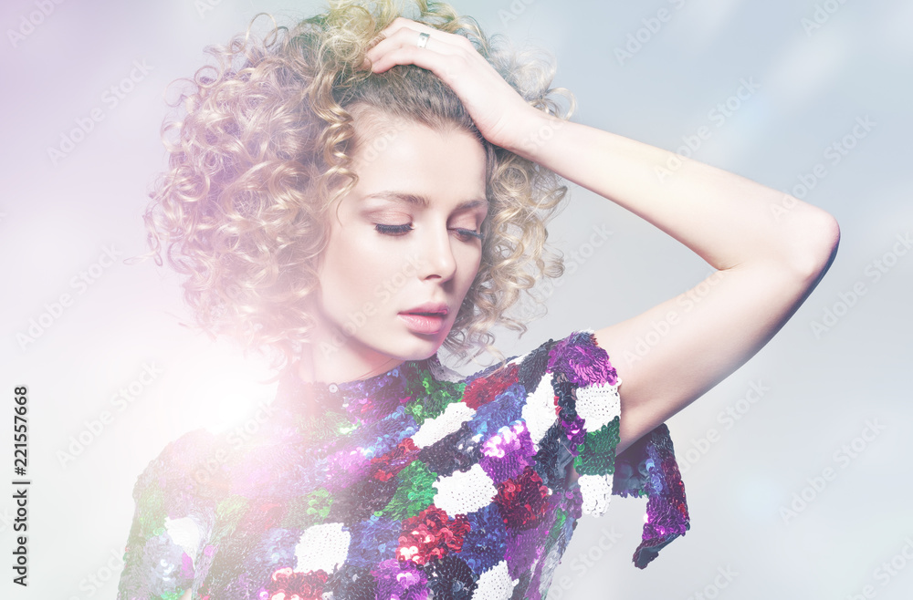 Fototapeta premium A young woman in a shiny dress dancing in the bright rays