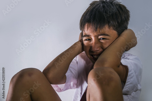 bullying victim portrait of young sad and scared kid in school uniform sitting alone crying depressed and frightened suffering abuse problem being bullied