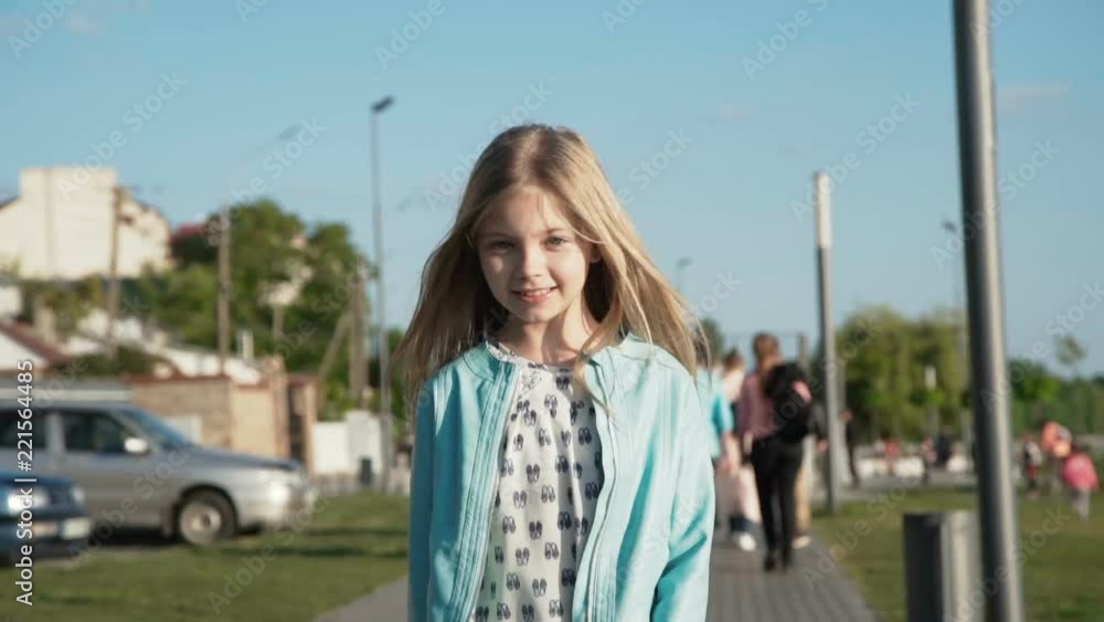 Beautiful little girl walks and turns around at camera at sunny quay Beautiful little girl walks and turns around at camera at sunny quay