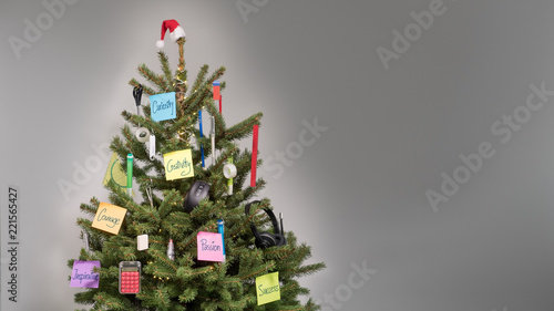 Christmas tree with decorations of business accessories and colored post-it notes with keywords and wishes in front of a light gray background, copy space, nobody 