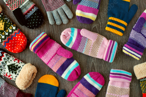 Mittens for winter. View from above. Many multicolored mittens on a wooden background. Warm clothing for hands in the cold season. photo