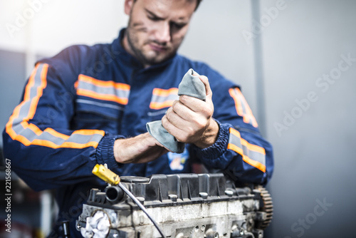 Canvastavla Serious professional mechanic wiping hands with rag after hardworking on car engine