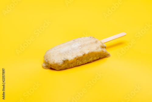 studio shoot of green bean popsicle starts melting on yellow background