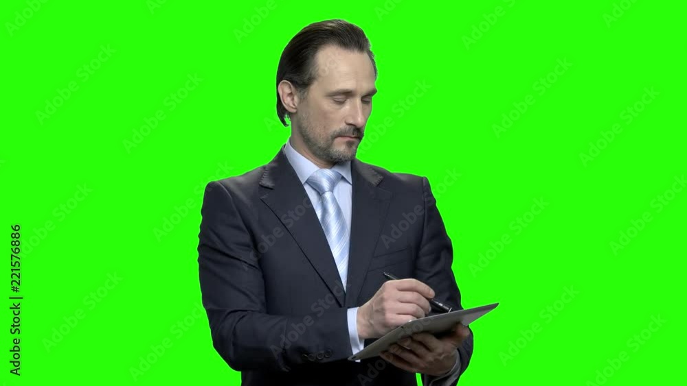 Portrait of businessman with tablet and pen. Making notes. Green hromakey background for keying.