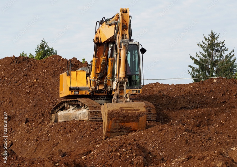 Front view of an excavator on a small hill of earth digged by itself Front view of an excavator on a small hill of earth digged by itself