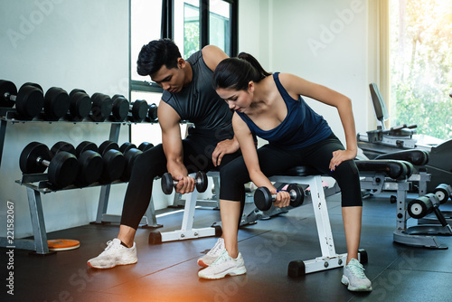 The beauty lady and handsome man are wearing exercise suit,raising dumbbell for built arm muscle,blurry light around