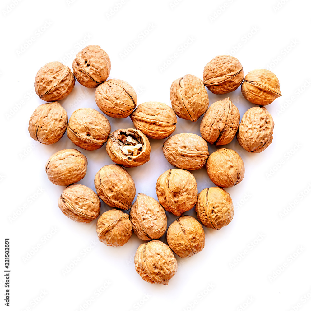 whole walnuts scatter with one cracked nut in heart shape isolated on white whole walnuts scatter with one cracked nut in heart shape isolated on white