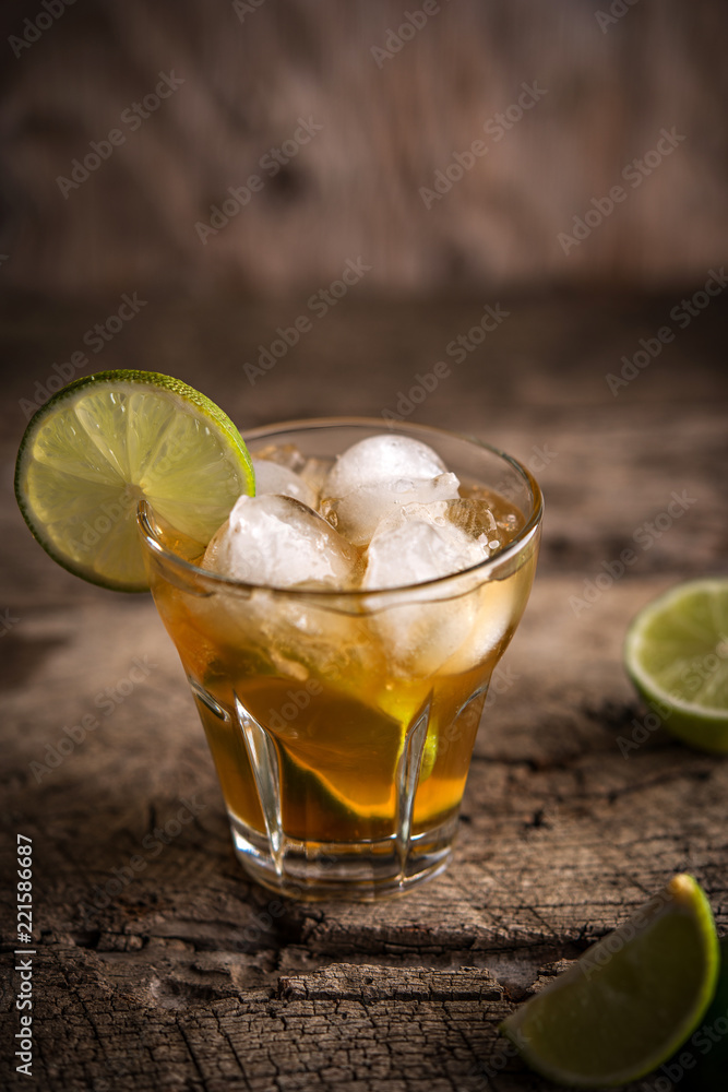Ice tea in glas served with lime over rustic table