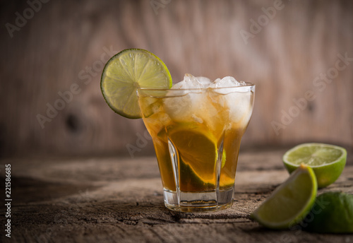Refreshing ice drink with lime over wooden background
