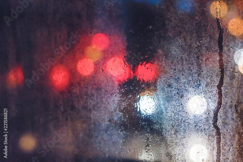 Rain drops on the window in the night city. Blurred background