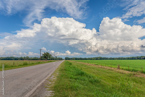 Country road in Oklahoma with white clouds against a blue sky.