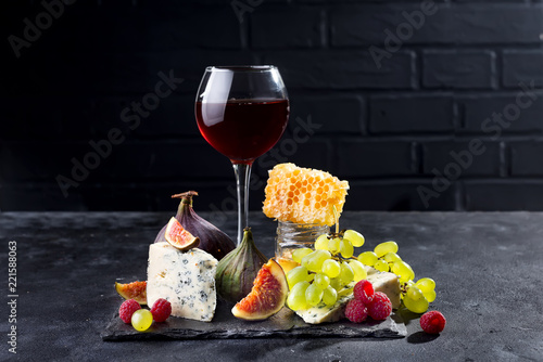 Fototapeta Naklejka Na Ścianę i Meble -  Grape, cheese, figs and honey with a glasses of red on a stone black background, copy space