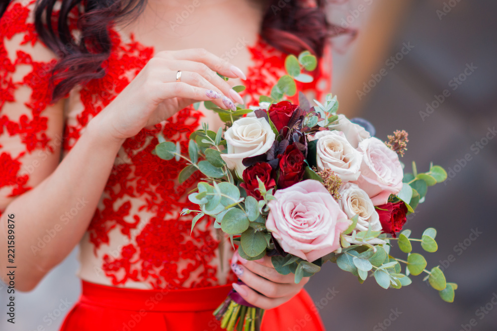 The bride in red wedding dress is holding bridal bouquet of roses Stock  Photo | Adobe Stock