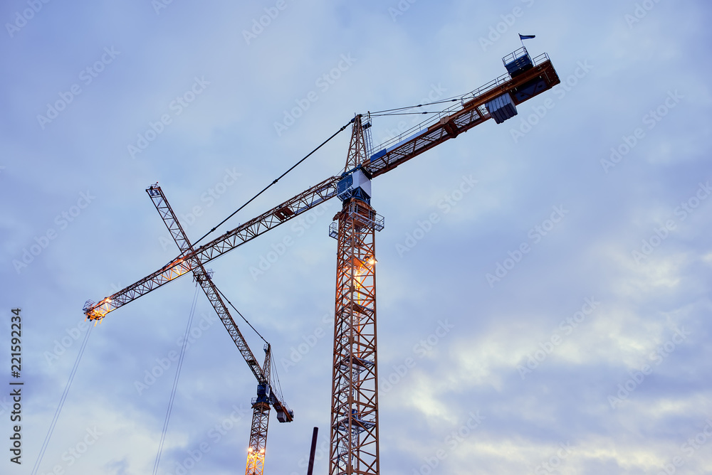 Construction cranes against the dark sky background