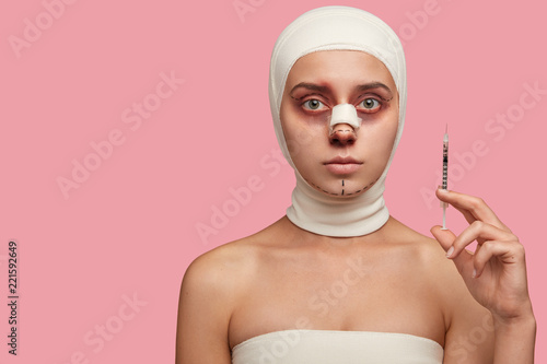 Photos Photo of woman has marked face with lines, bruised skin, holds syringe for makin