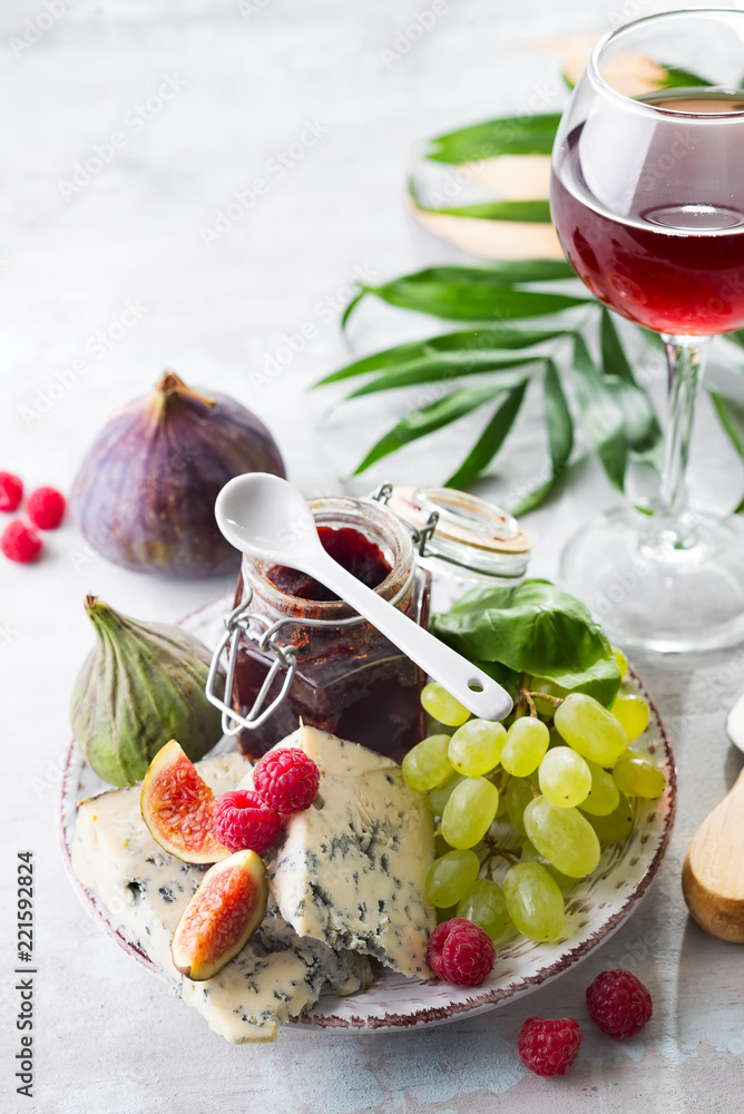 delicacy blue cheeses, fruit and jam in jar with red wine in glass on white stone background, copy space delicacy blue cheeses, fruit and jam in jar with red wine in glass on white stone background, copy space