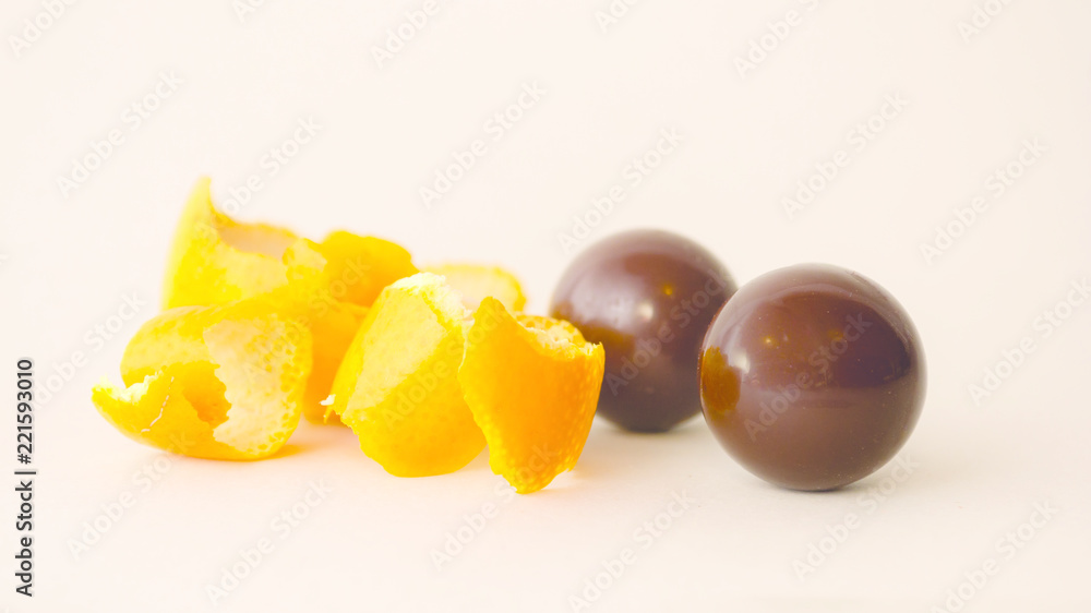 Artisan chocolate and orange sweets isolated with its filling and/or flavour on the side, white background