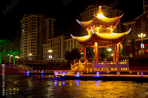 Chinese Pagoda at night time  City Architecture  China Culture Tourism. Multi-Color Lights  lake with calm water. Skyscrapers in the background  City Landmark. Chinese Traditional Architecture