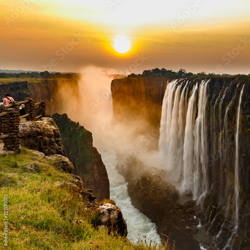 Bild auf Leinwand Victoria falls sunset with orange sun and tourists