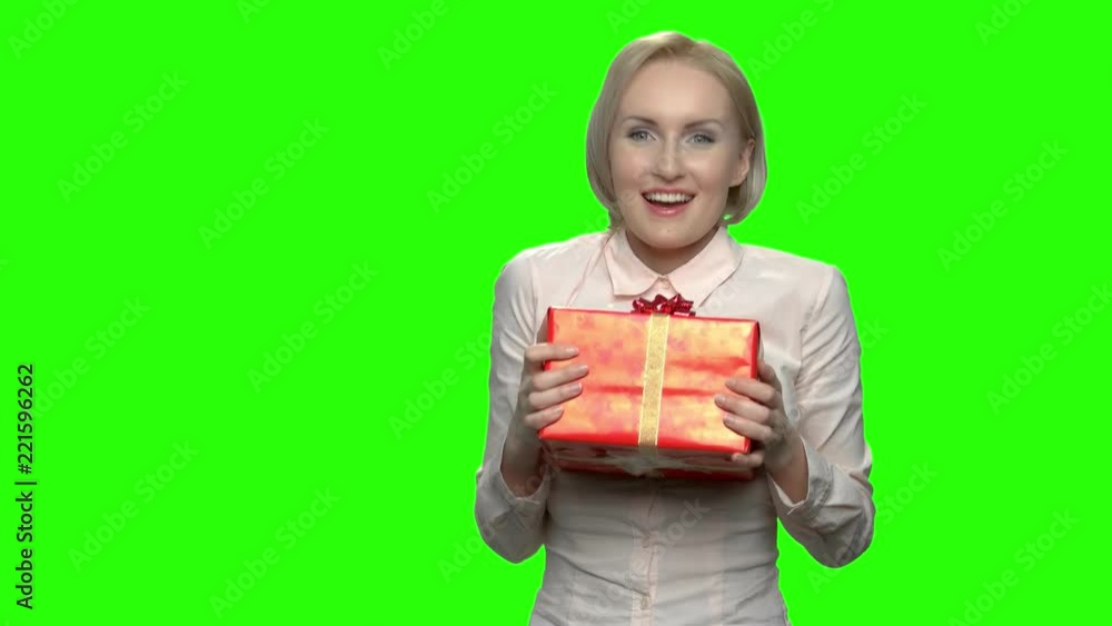 Portrait of woman admires her gift box for birthday. Excited mature caucasian woman with red gift box and ribbon. Green hromakey background for keying. Portrait of woman admires her gift box for birthday. Excited mature caucasian woman with red gift box and ribbon. Green hromakey background for keying.