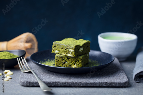Matcha green tea cake, bars, brownie with white chocolate on a plate. Grey background. Copy space.
