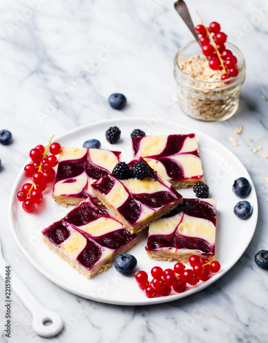 Oatmeal, oat bars with fresh berries on a white plate. Marble background. Healthy breakfast.