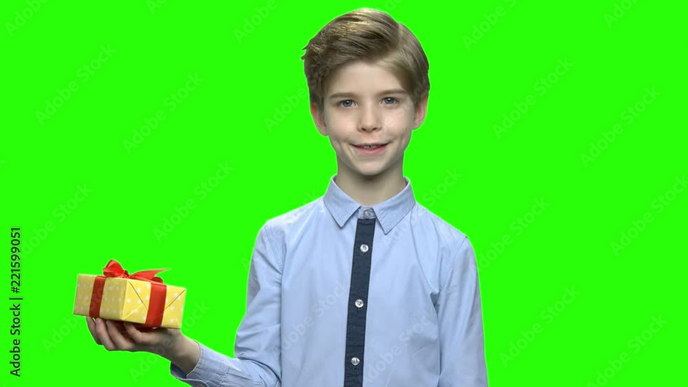 Handsome child holding yellow gift box with red ribbon. Green hromakey background for keying. Handsome child holding yellow gift box with red ribbon. Green hromakey background for keying.