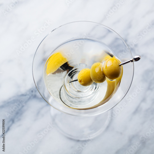 Martini cocktail with green olives on marble board. Copy space. Top view. photo